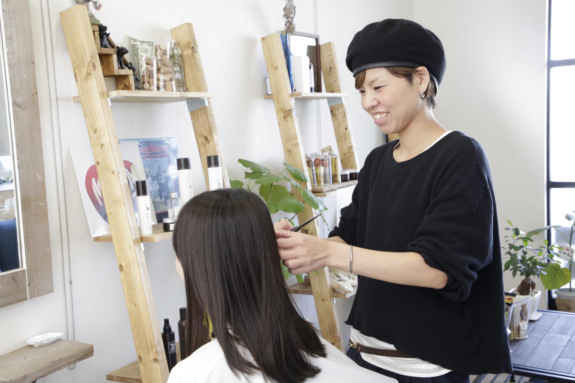 代表の濱さんが女性客のヘアカットをしている様子を写した写真。