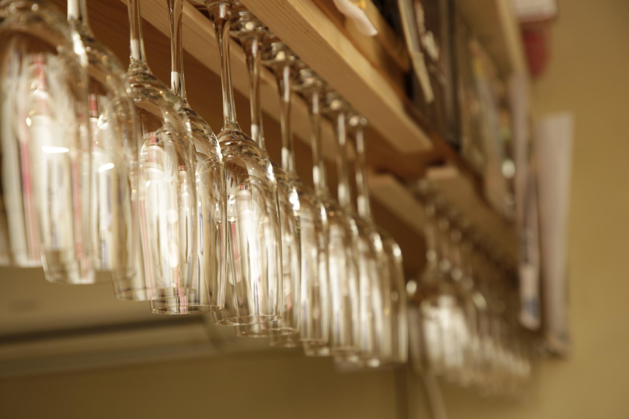 グラスハンガーにたくさんのワイングラスが掛けられている様子を写した写真。